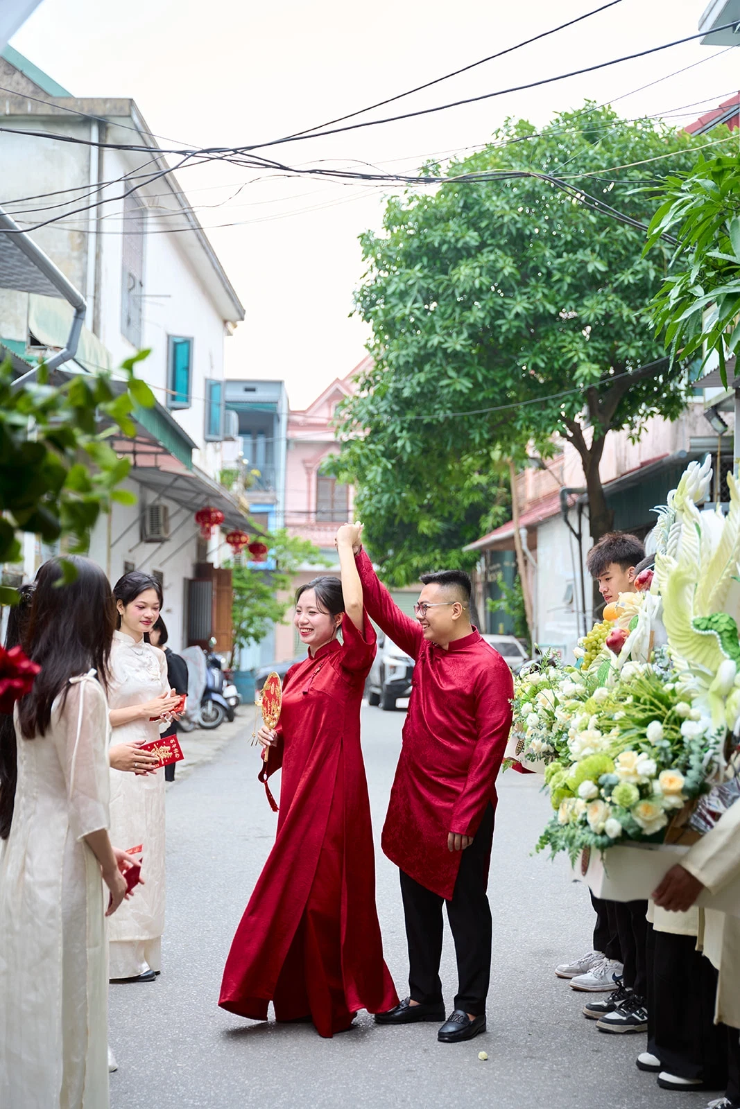 Cô dâu chú rể áo dài đỏ vui đùa cùng người thân trước nhà