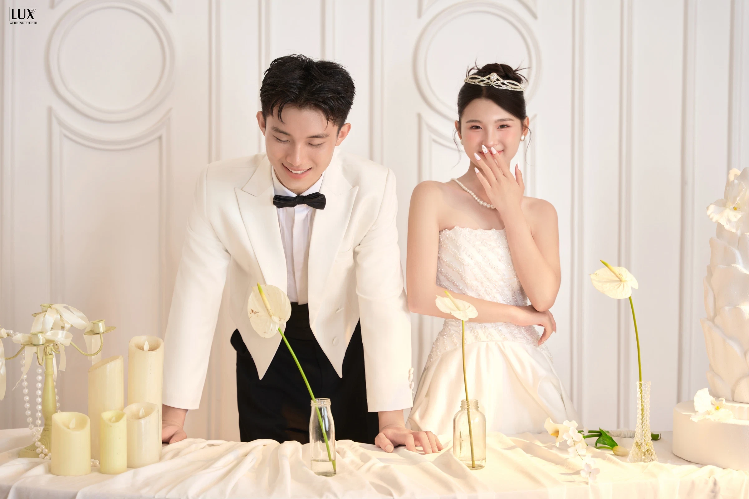 Cô dâu chú rể bên bàn tiệc trắng trong studio
