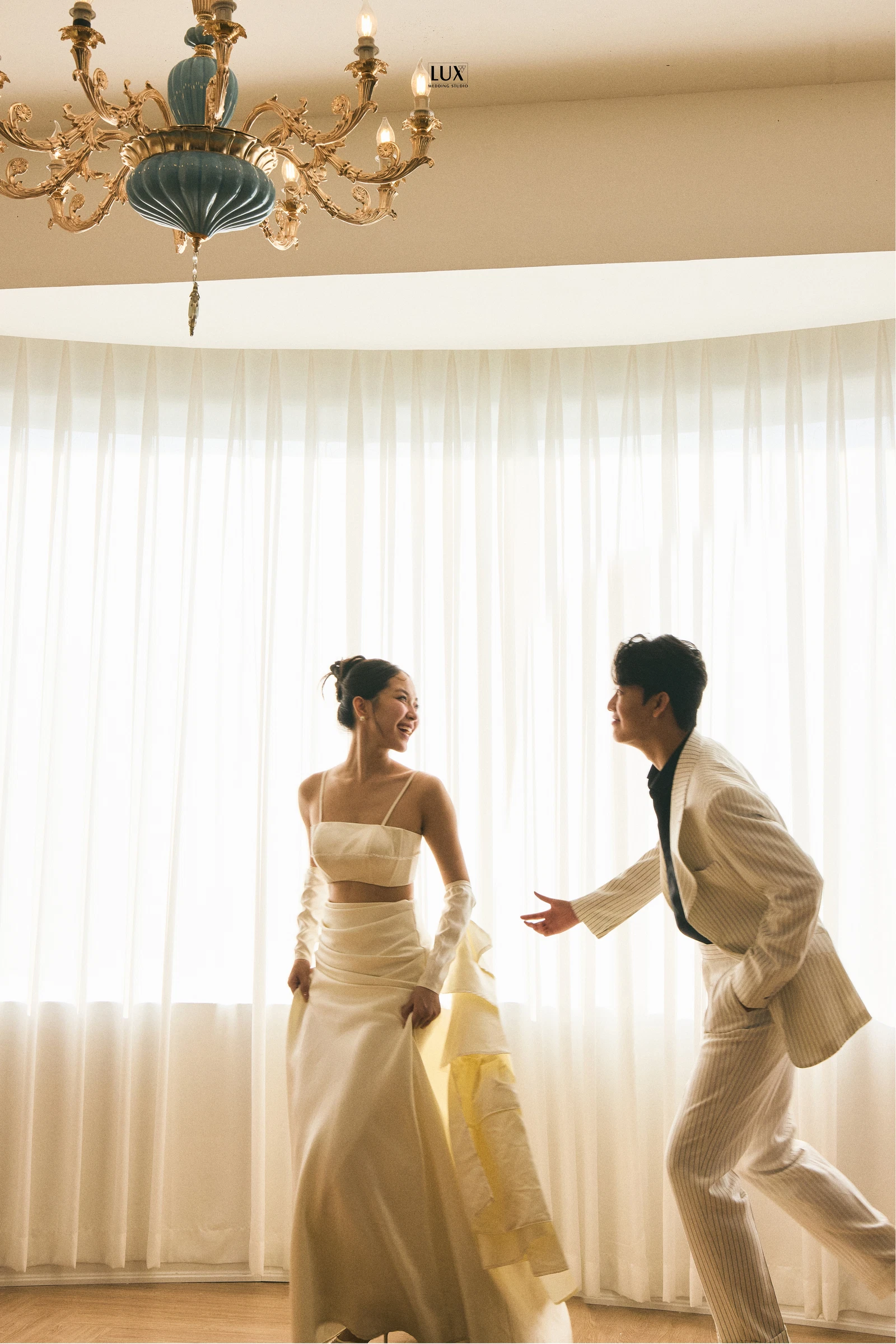 Cặp đôi hướng về nhau trong căn phòng có rèm cửa sáng, ảnh LUX
