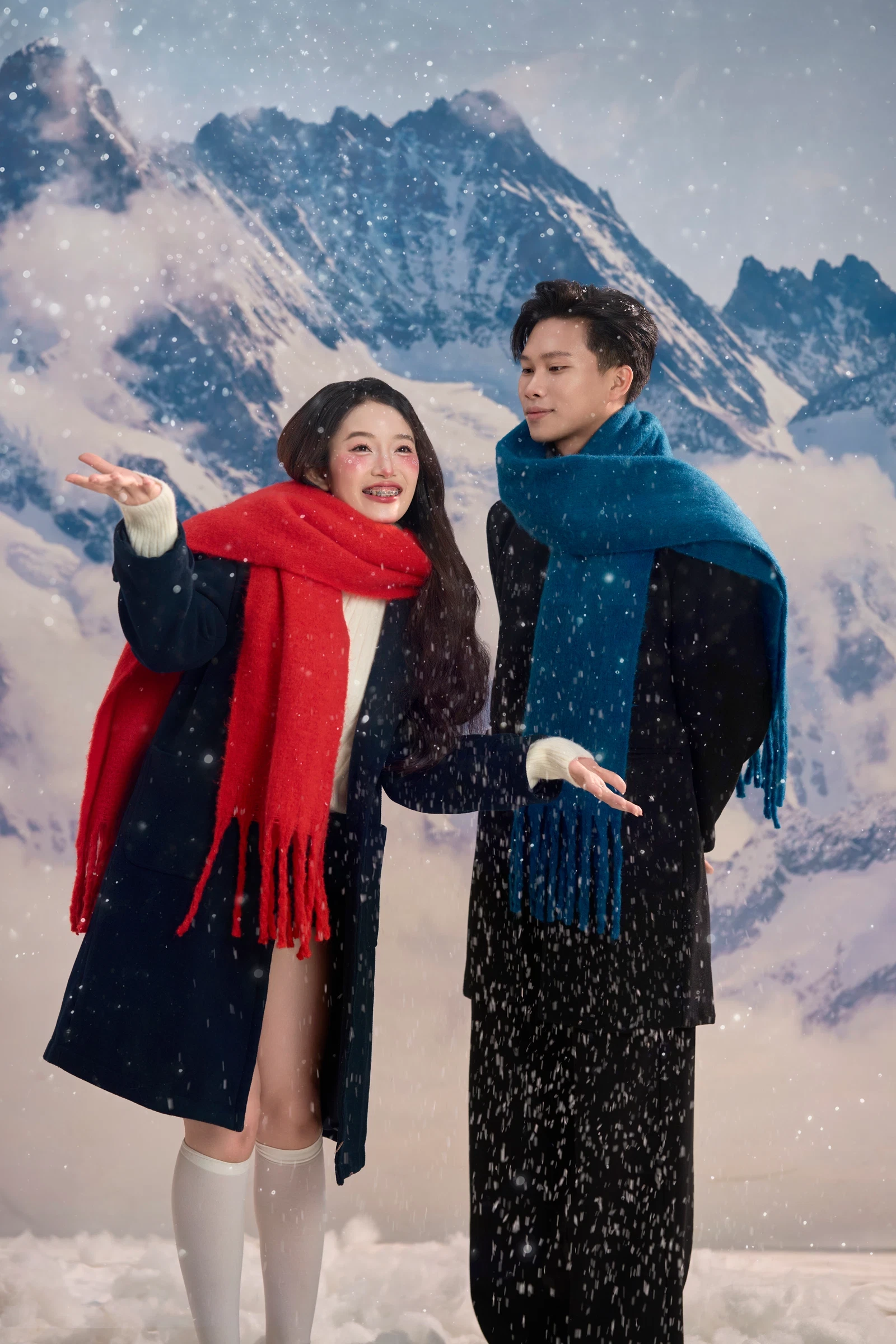 Cặp đôi quàng khăn len trước phông núi tuyết