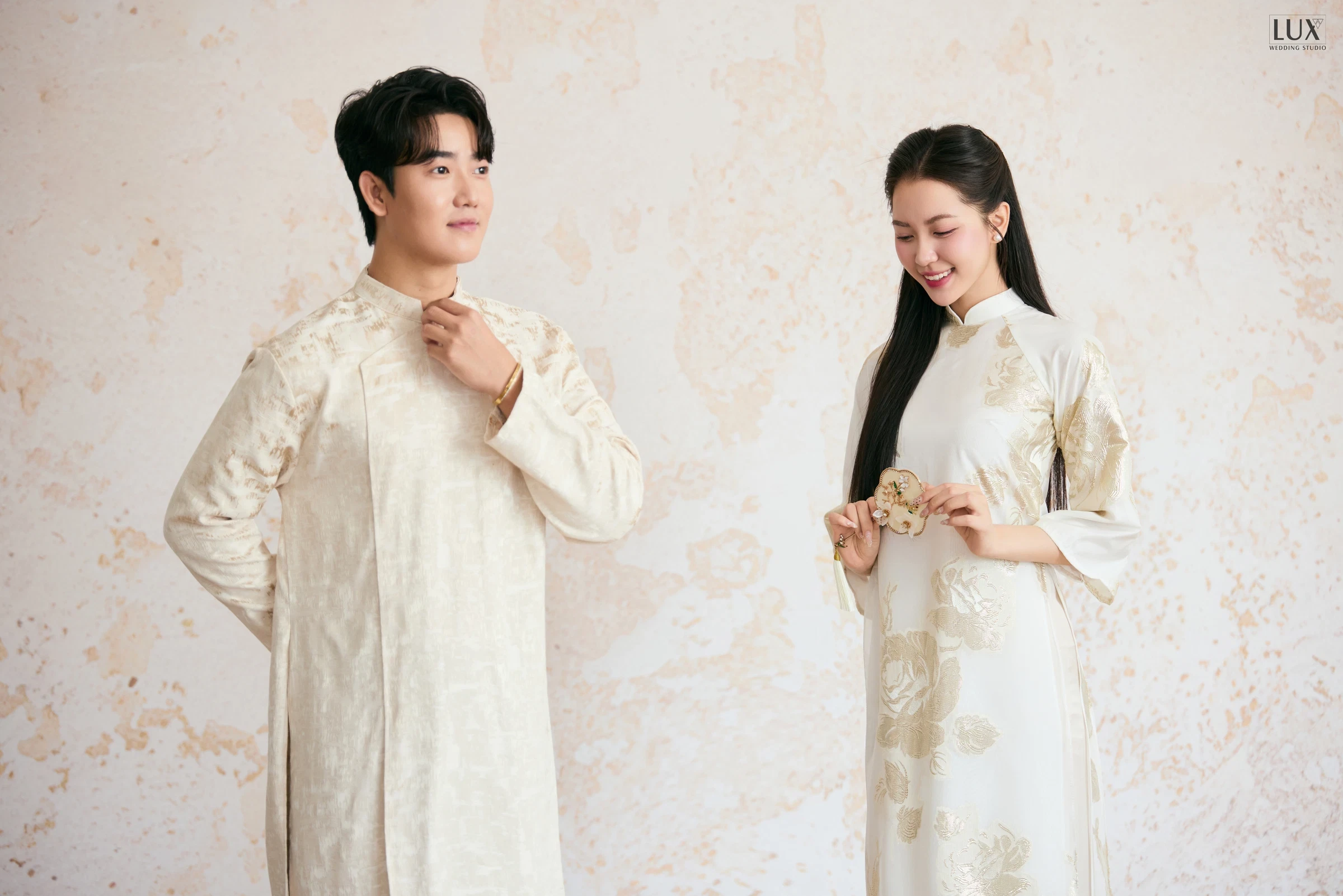 Cặp đôi áo dài kem và trắng thêu hoa trên phông sáng